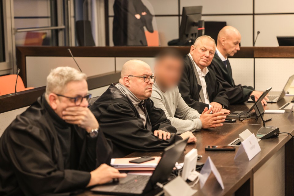 Defendant sits between lawyers in a courtroom.