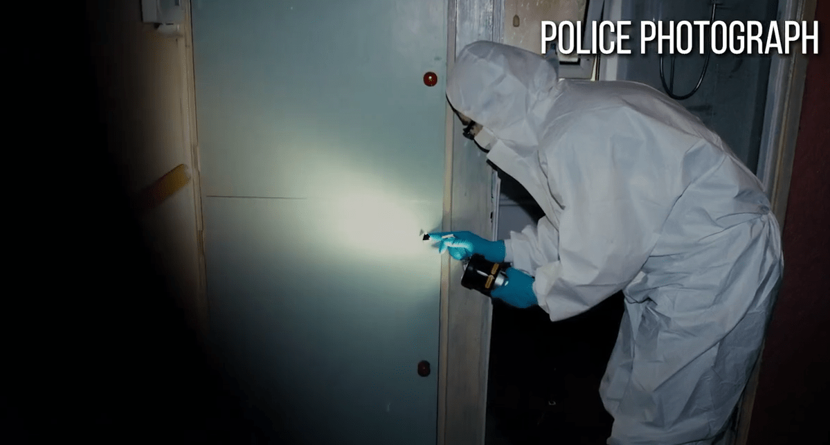 Police photograph of a forensic investigator examining a wall.