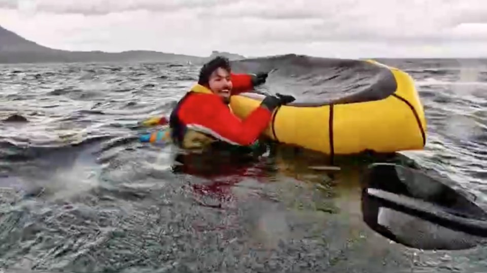 Man holding onto overturned packraft after being swallowed by a whale.