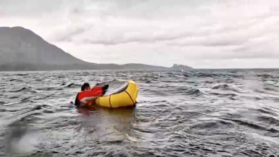 Man clinging to an overturned raft in choppy water.