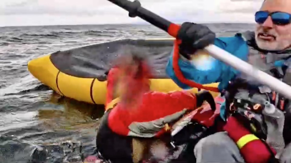 Video still of a man in a kayak helping his son who was swallowed by a whale and then spat out unharmed.