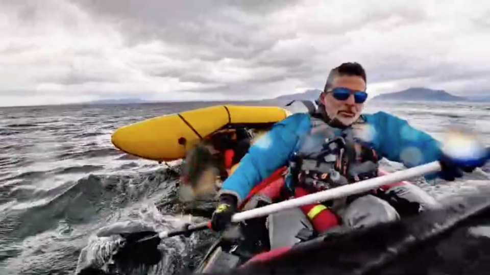 A man kayaking in rough water, another kayak is visible behind him.