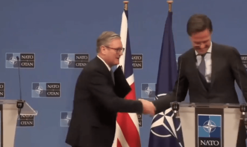 Two men shaking hands at a NATO press conference.