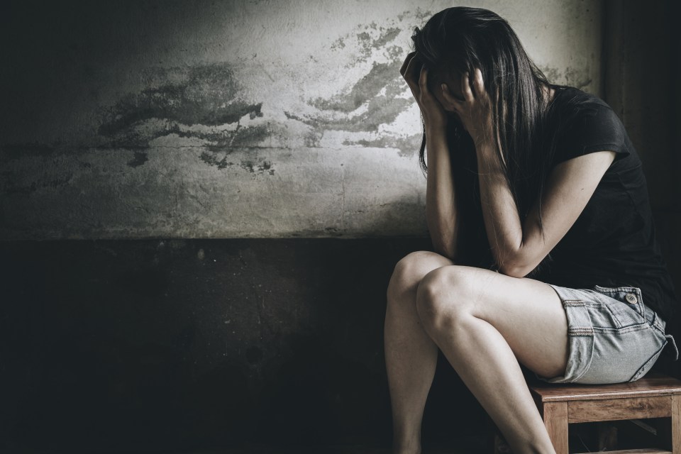 A distressed woman sits with her head in her hands.