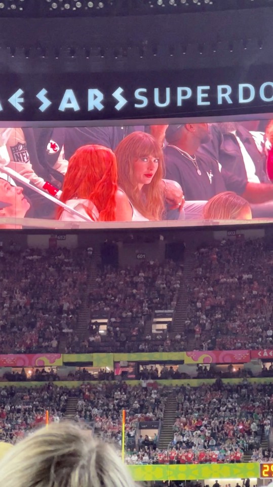 Taylor Swift shown on a jumbotron at a stadium, booed by fans.