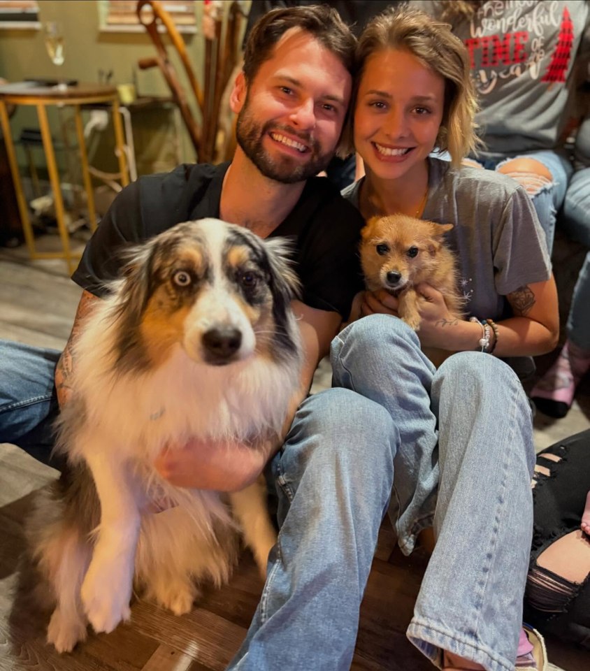 A couple and their two dogs sitting on the floor.