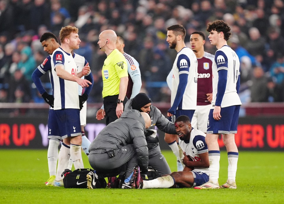 Kevin Danso of Tottenham Hotspur receiving medical attention on the field.