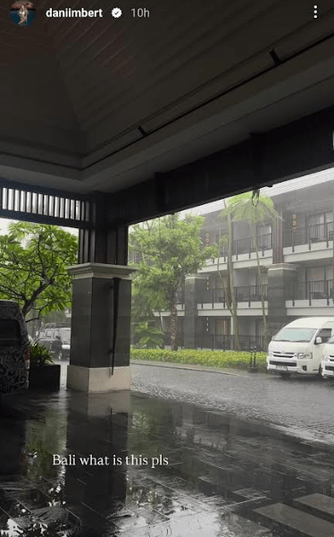 Rainy scene in Bali, showing a building and vehicles.