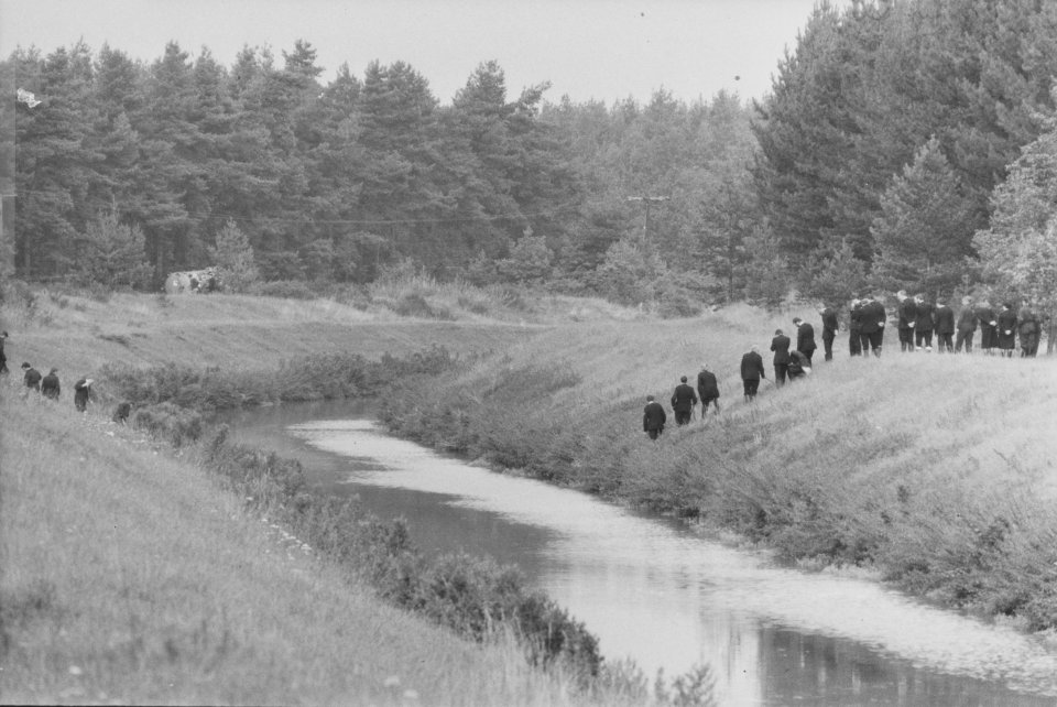 Police investigating a crime scene by a canal.