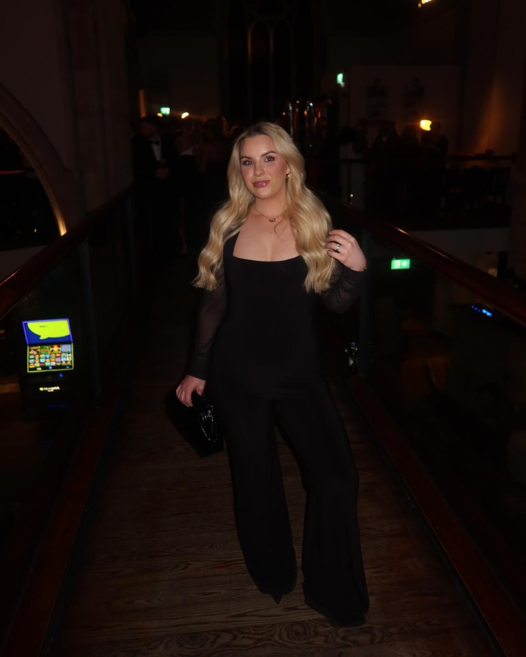 Woman in black jumpsuit at an event.