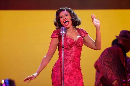 A woman in a red dress sings into a microphone.