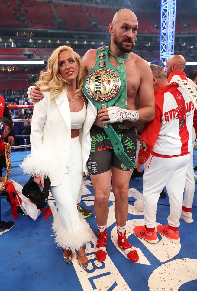 Tyson Fury celebrating his victory with his wife, holding the WBC World Heavyweight Championship belt.