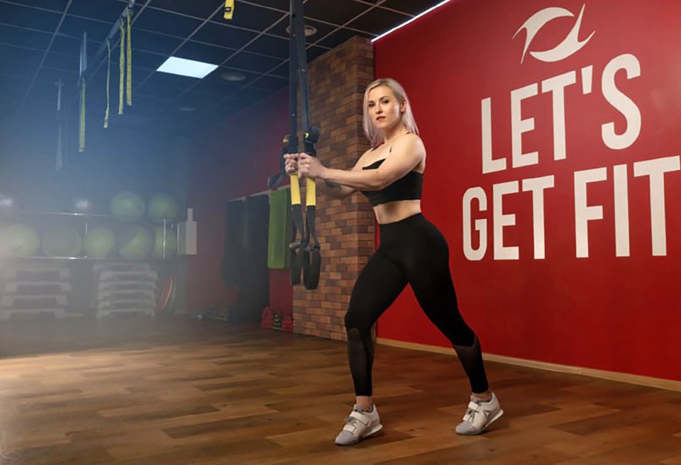 Woman doing TRX workout in gym.