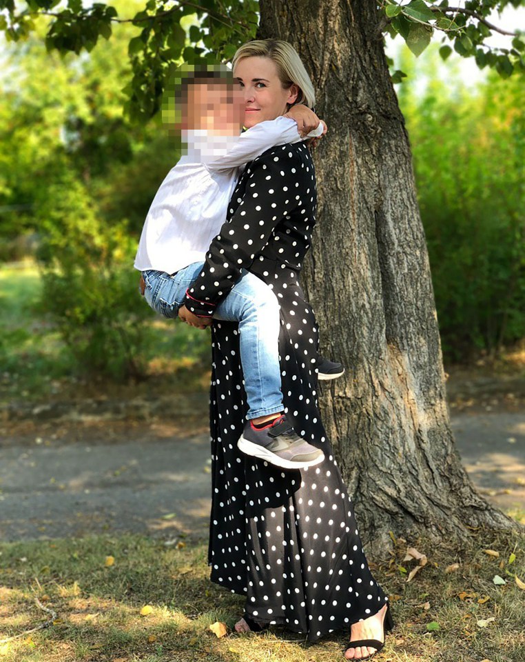 A woman in a polka dot dress holds a child.