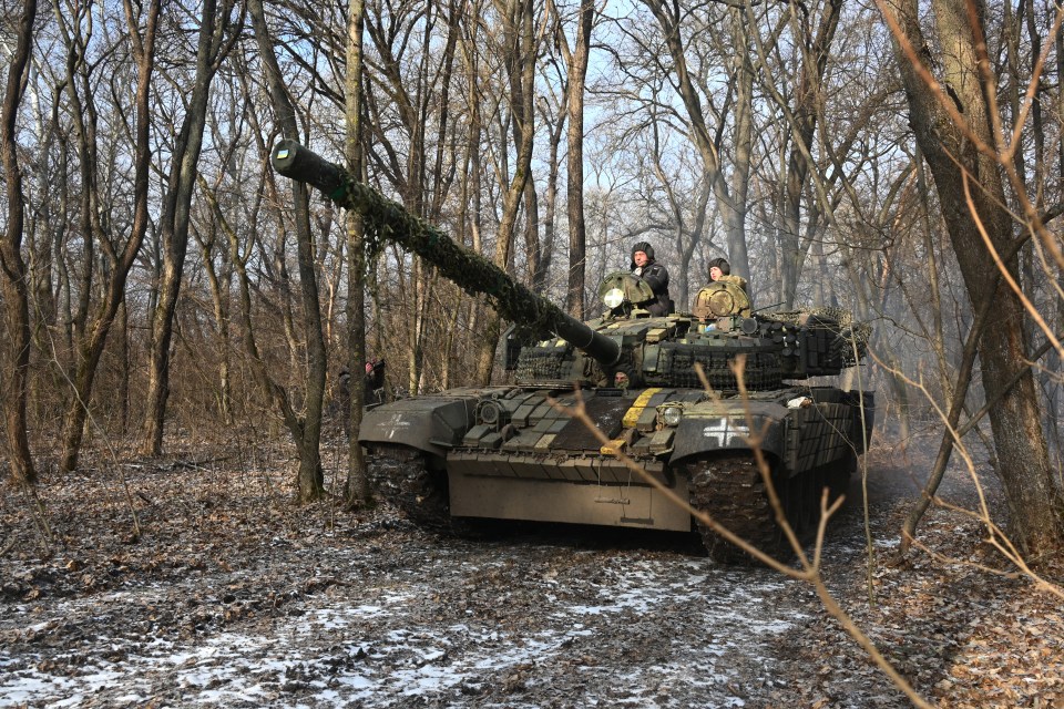 Ukrainian servicemen on a T-72 tank in a forest.