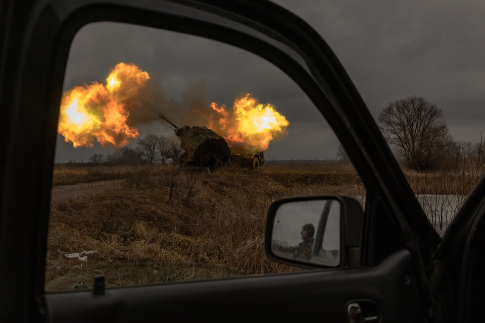 A Ukrainian soldier reflected in a car mirror watches an Archer Howitzer fire.