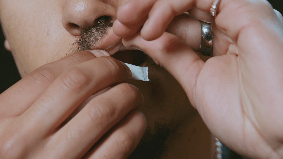 Close-up of a person placing a nicotine pouch in their mouth.