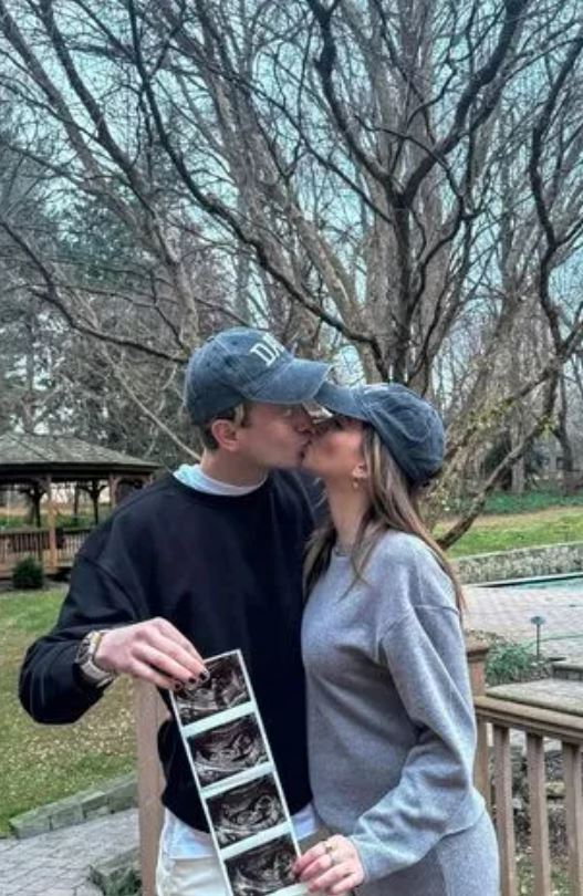 Couple kissing and holding ultrasound photos.