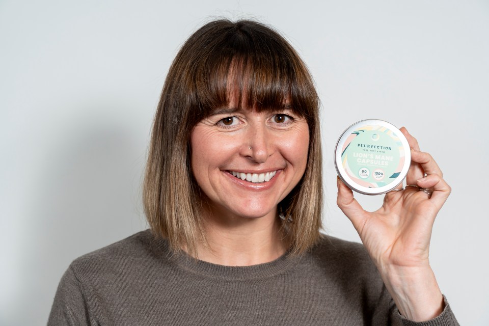 Woman holding a tin of Lion's Mane capsules.