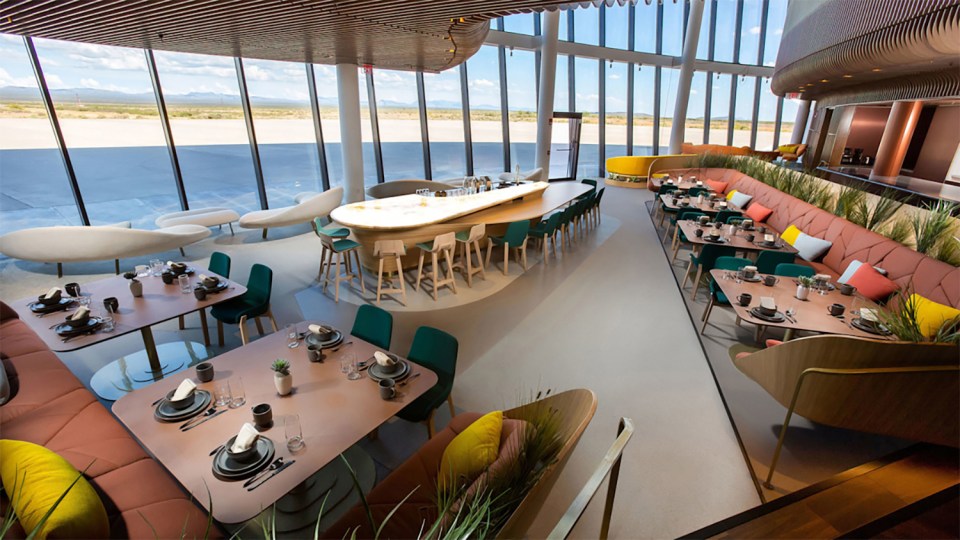 Interior view of a restaurant with large windows overlooking a runway.