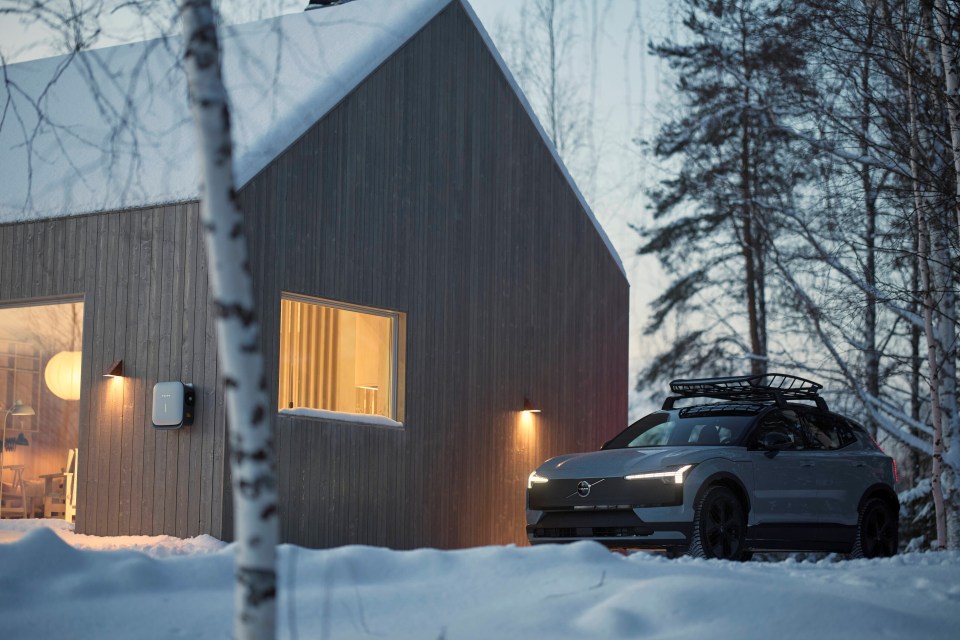 Volvo EX30 Cross Country parked outside a modern home in the snow.