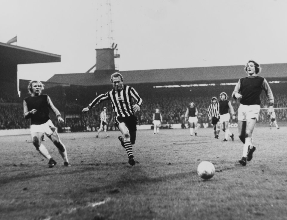 Black and white photo of a soccer game at Upton Park.  A Newcastle player runs with the ball.