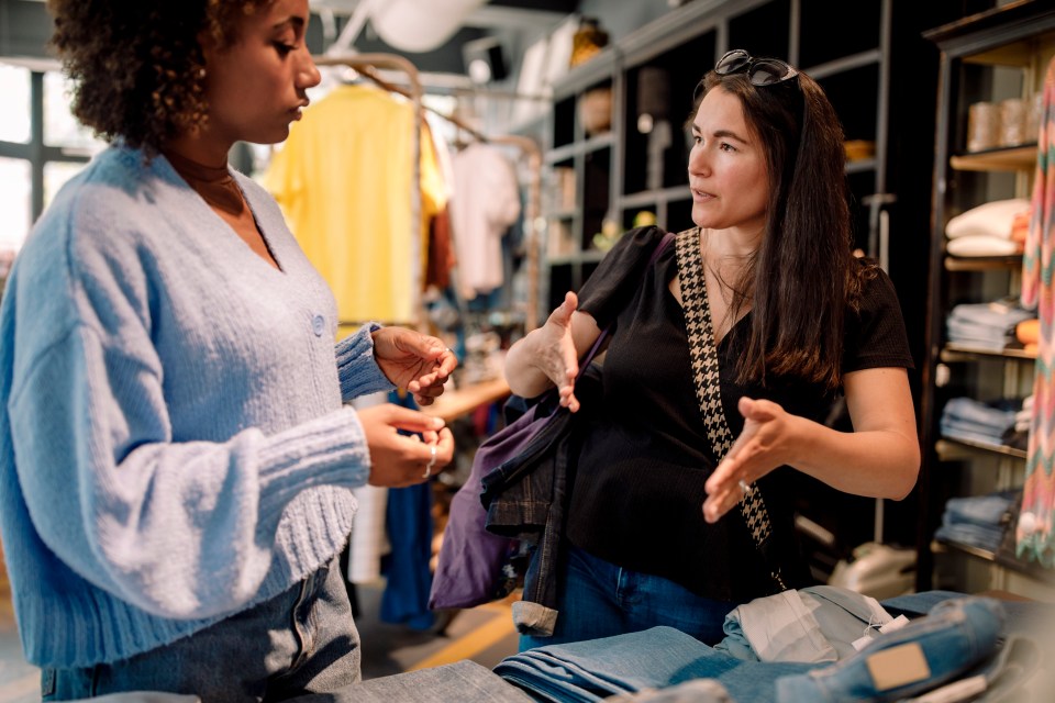 Two women shopping for clothes in a store.