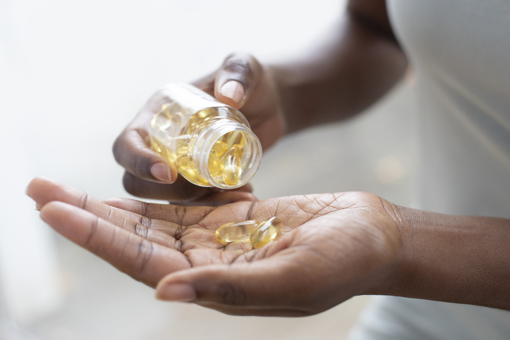 Person pouring capsules into their hand.