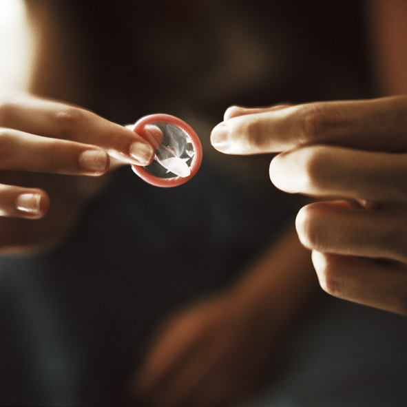 Fingers holding a condom.