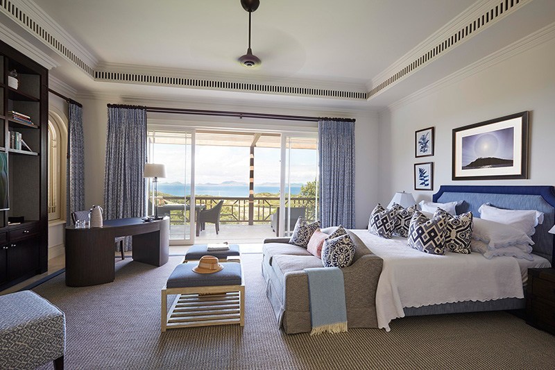 Ocean view bedroom with king-size bed and desk.