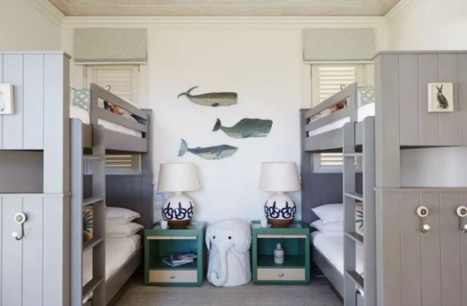 Children's bedroom with two sets of bunk beds and whale wall art.