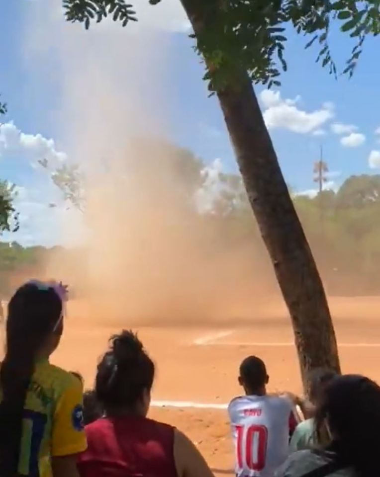 Spectators watching a dust devil on a soccer field.