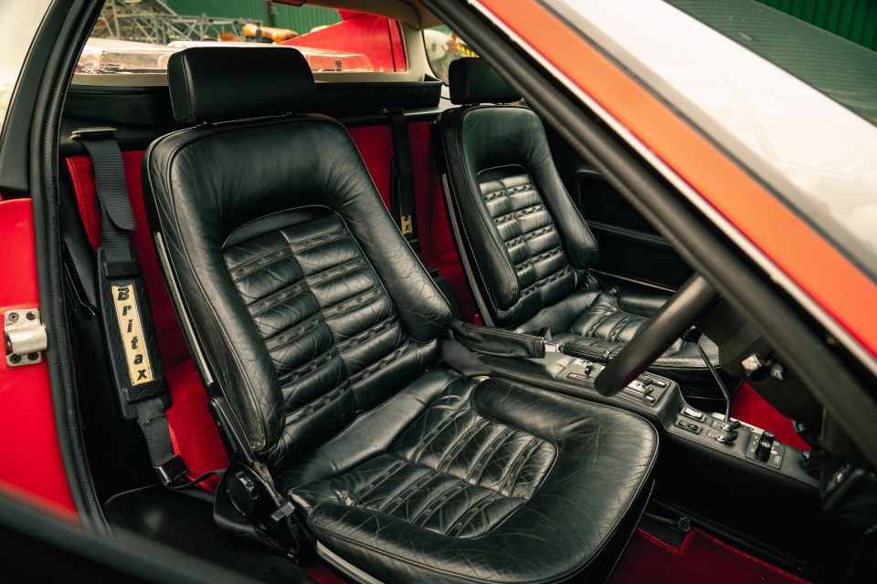 Interior view of a vintage red Ferrari's black leather seats.