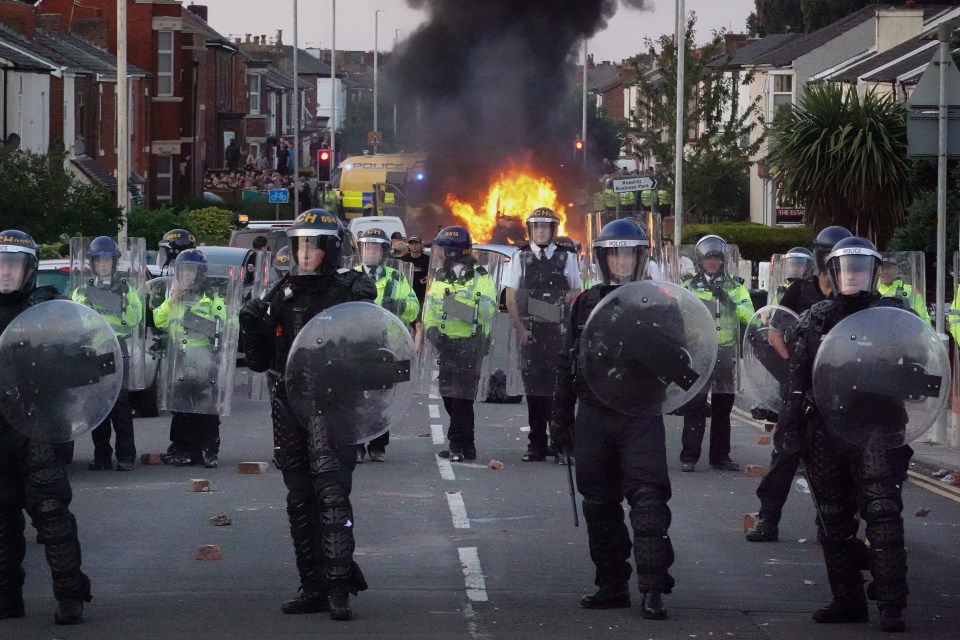 Riot police in Southport, England, face protesters during a demonstration.