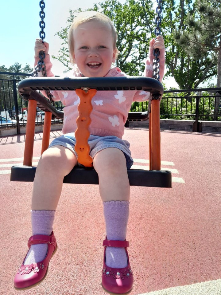 Toddler on a swing at a playground.