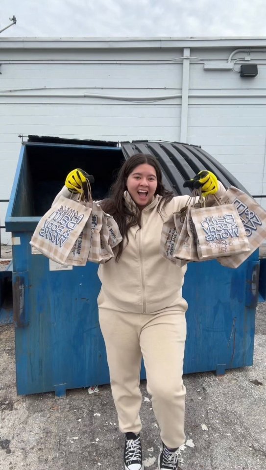 Woman holding bags of items retrieved from a dumpster.