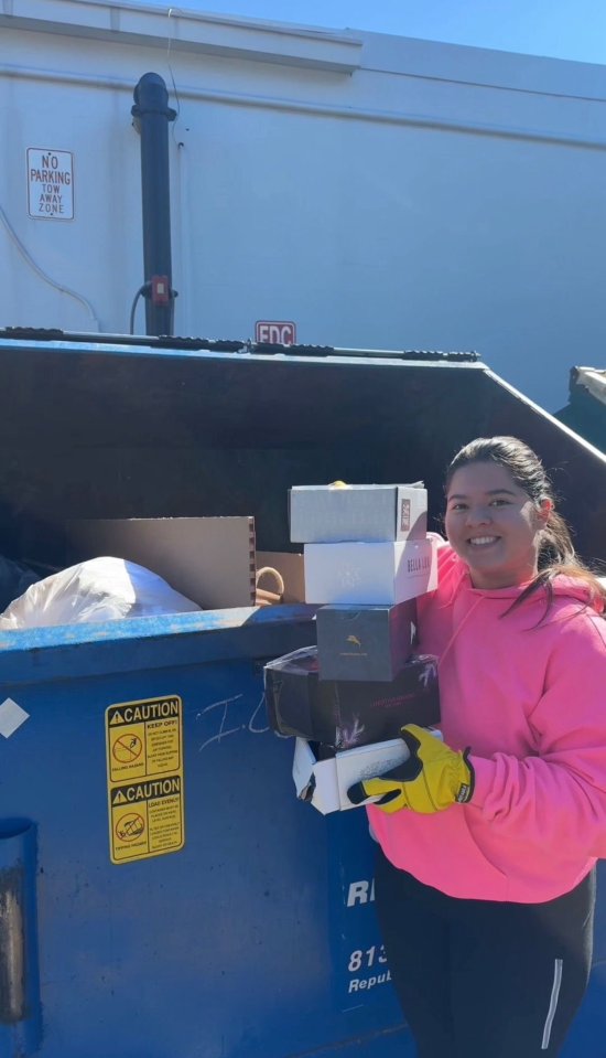 Woman holding boxes salvaged from a dumpster.