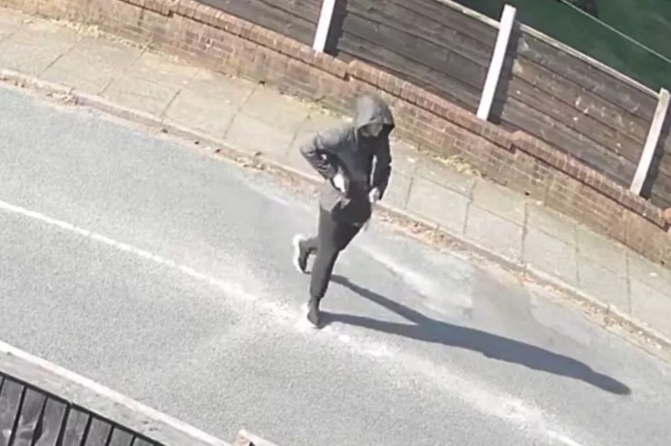 CCTV image of a suspect in a hooded jacket running down a street.