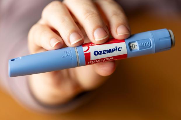 Close-up of a hand holding an Ozempic pen injection.