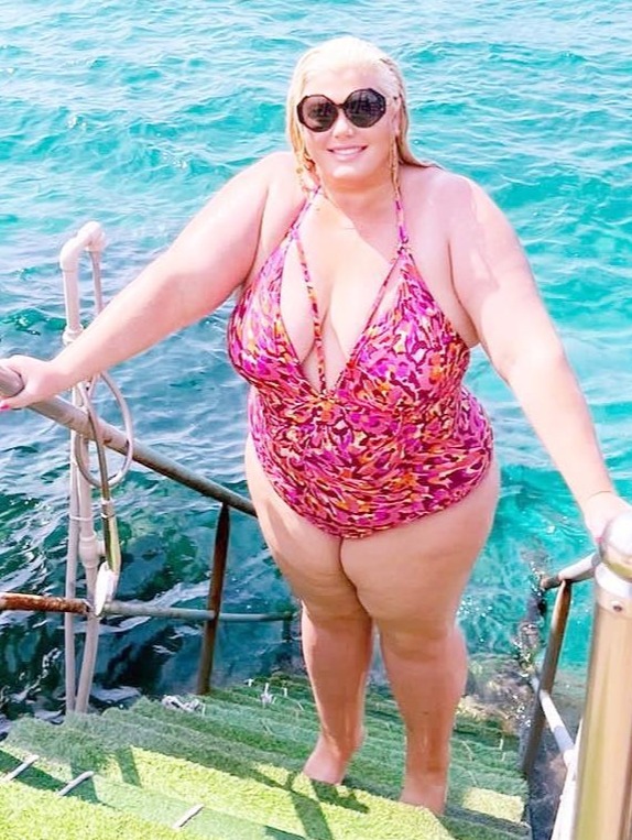 Gemma Collins in a plunging swimsuit, climbing stairs into the ocean.