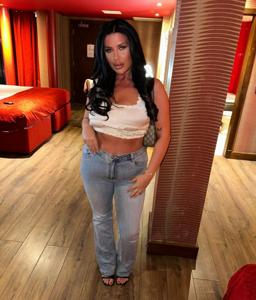 Woman in a crop top and jeans in a hotel room.