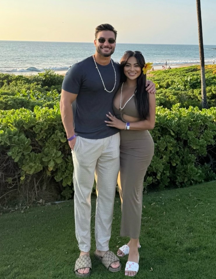 Couple posing on beach with ocean in background.