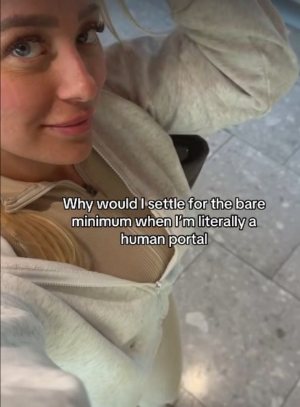 Screenshot of a woman in a beige jacket with text overlay: "Why would I settle for the bare minimum when I'm literally a human portal".