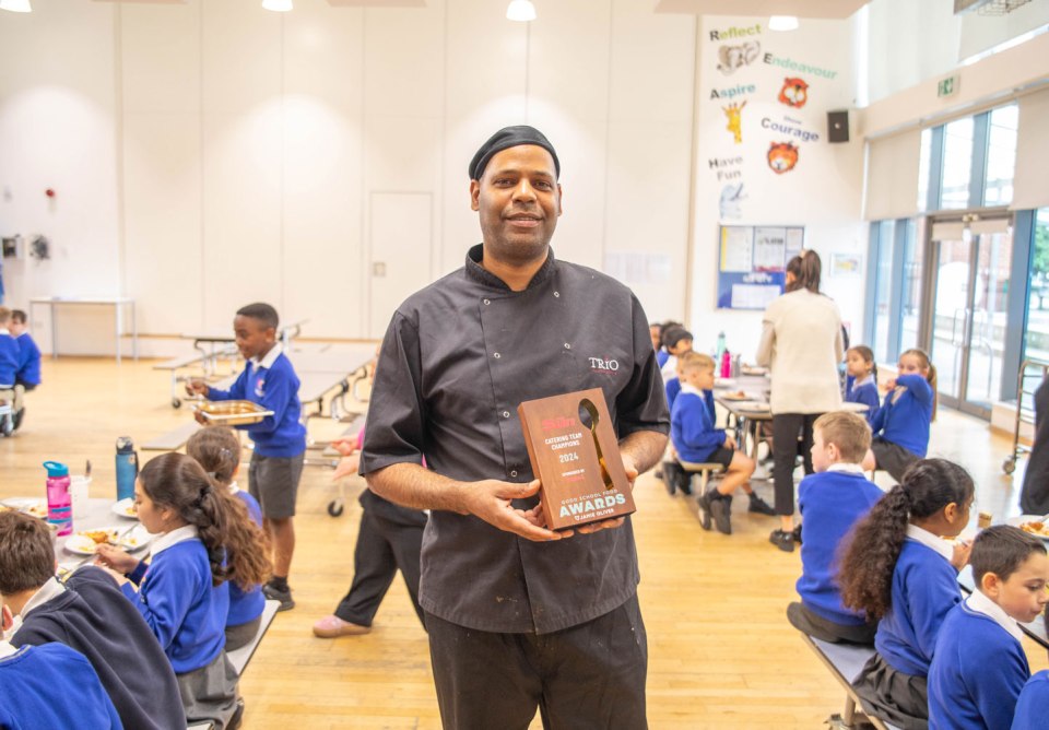 School chef holding a Good School Food Awards trophy.