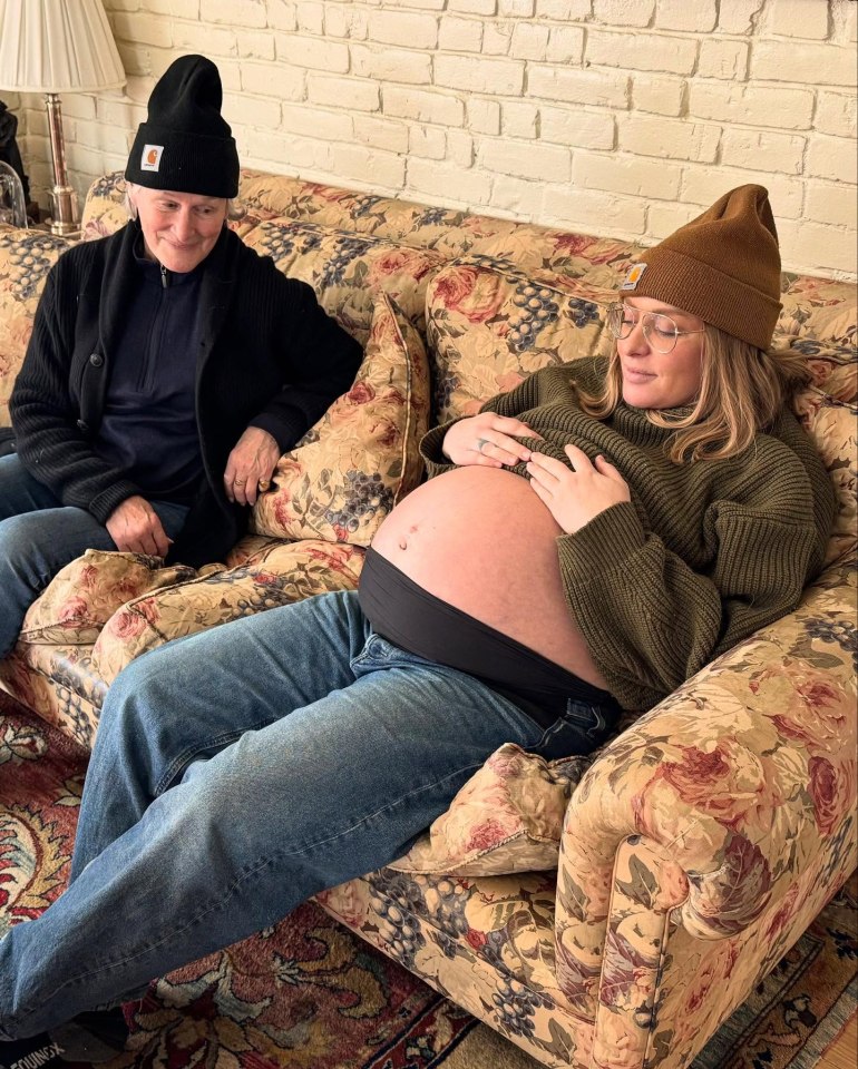 A pregnant woman and an older woman sitting on a floral couch.