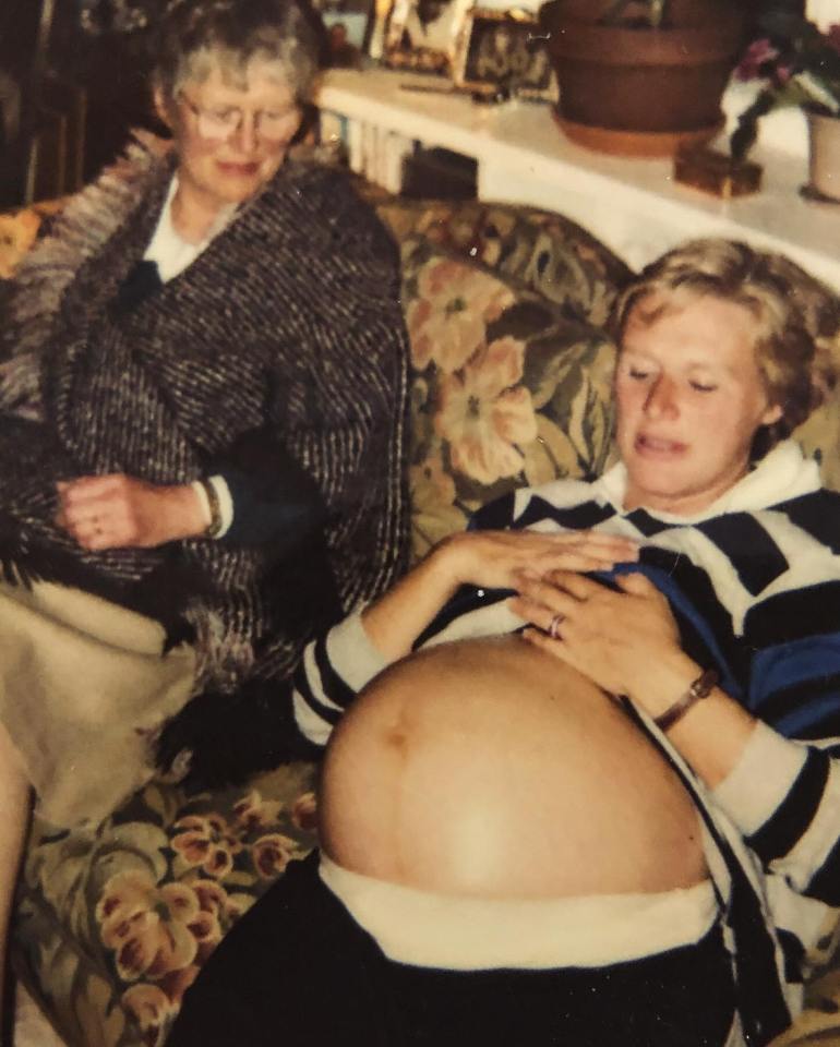 Photo of a pregnant woman holding her belly, with an older woman sitting beside her.