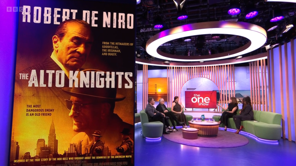 Screenshot of a film poster for "The Alto Knights" starring Robert De Niro, displayed on a TV show set.