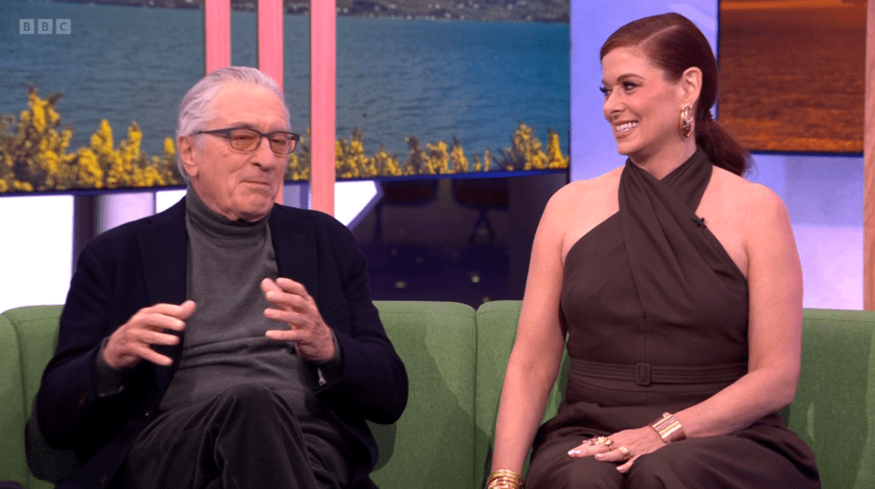 Robert De Niro and a woman sitting on a green couch.