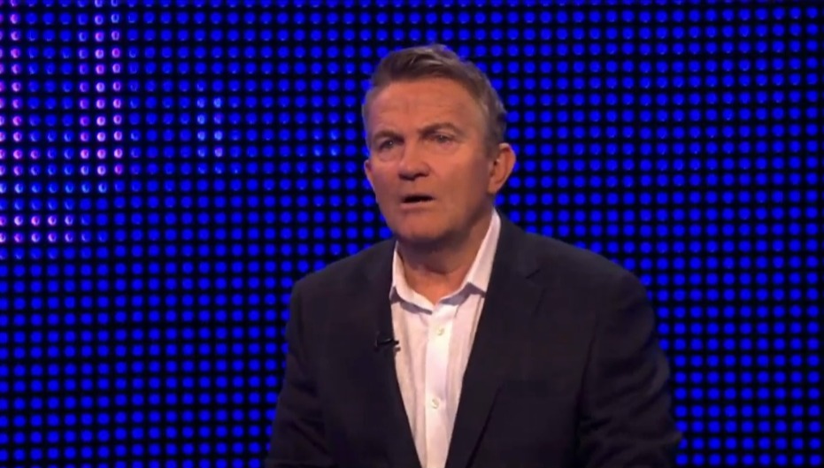 Screenshot of a man speaking in front of a blue screen.