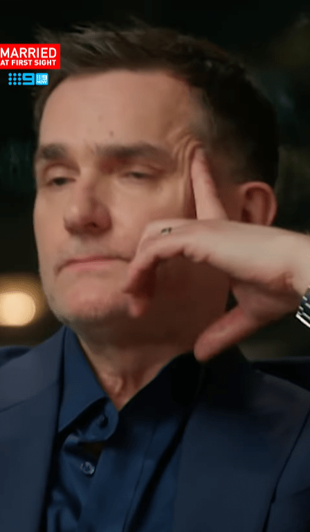 Screenshot of a man in a suit, hand to his face, from Married at First Sight.